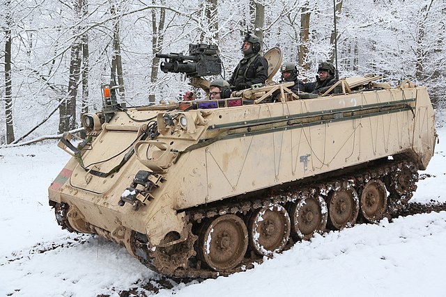 An armored personnel carrier in the snow in the woods.